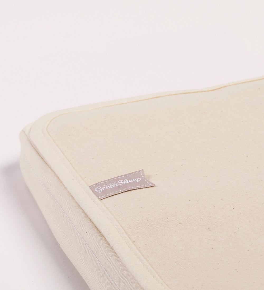 A close up of the corner of a Little Green Sheep Organic Crib Mattress Protector placed on a mattress