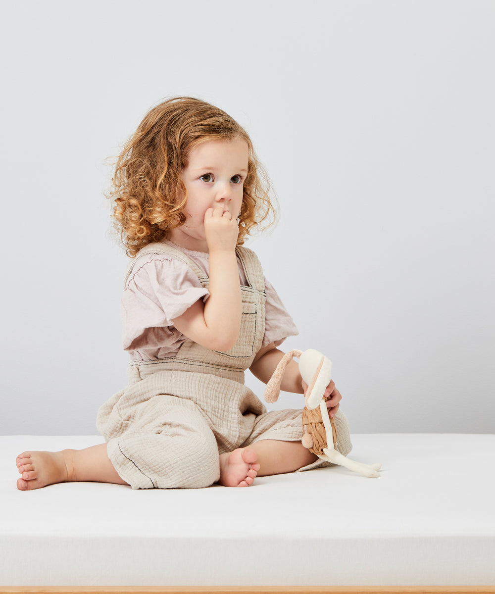 A child sitting on a Little Green Sheep Organic Single Jersey Fitted Sheet