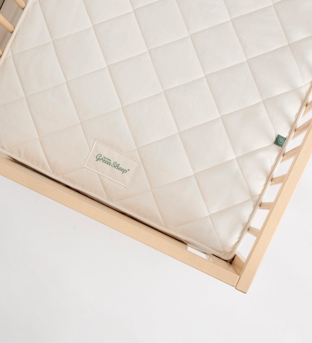 Little Green Sheep Twist Natural SnuzKot Mattress pictured in a wooden cot