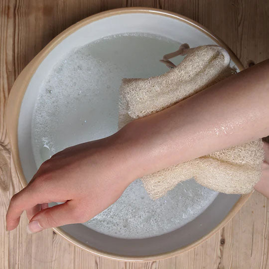 Person washing their arms with a LoofCo Body Loofah in soapy water