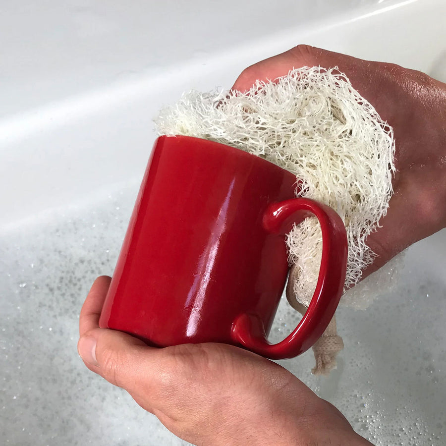 person washing a red mug with a LoofCo Washing-Up Pad