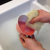 person washing a small pink and white bowl with a LoofCo Washing-Up Pad