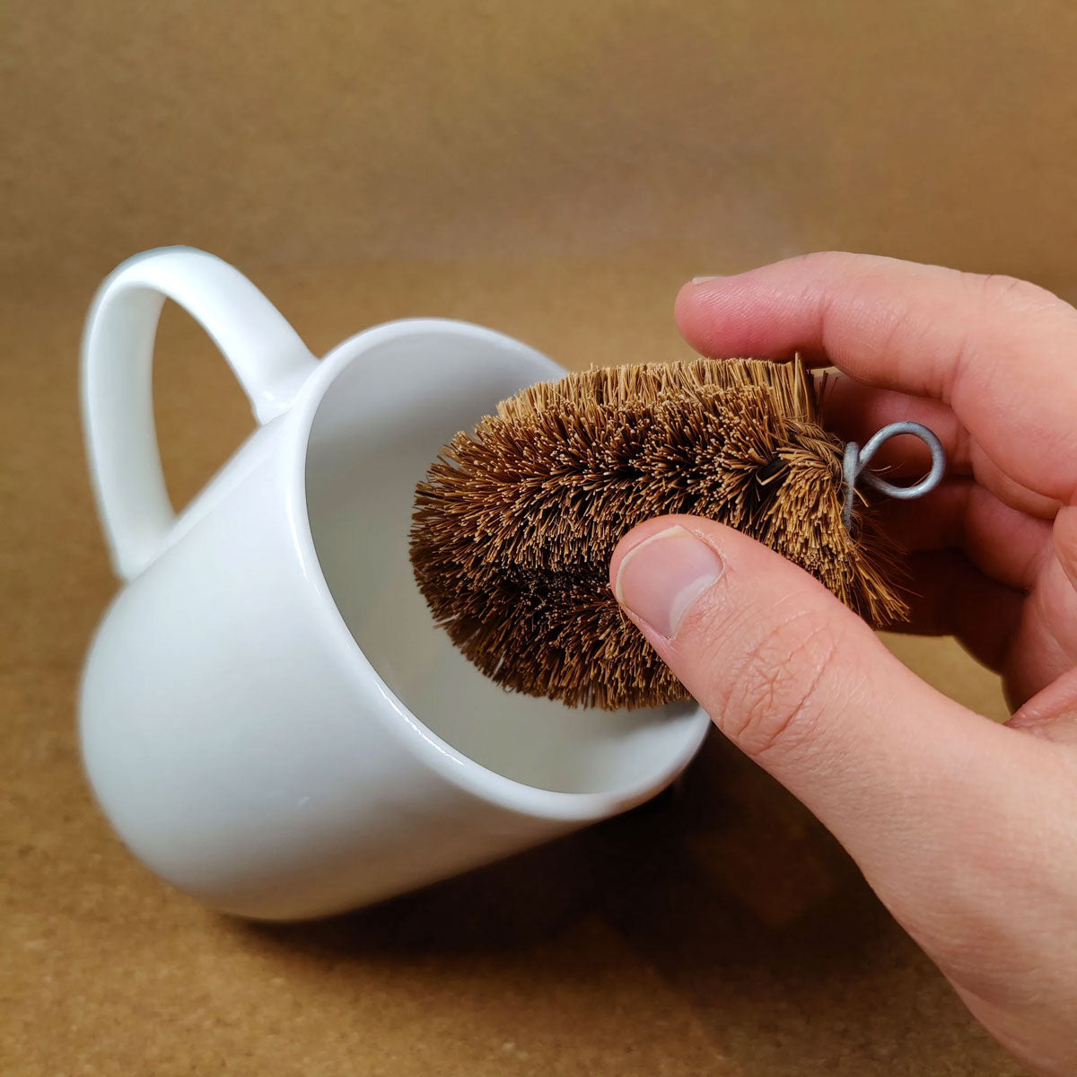 Small LoofCo Scrubbing Brush being used to scrub a plain white mug