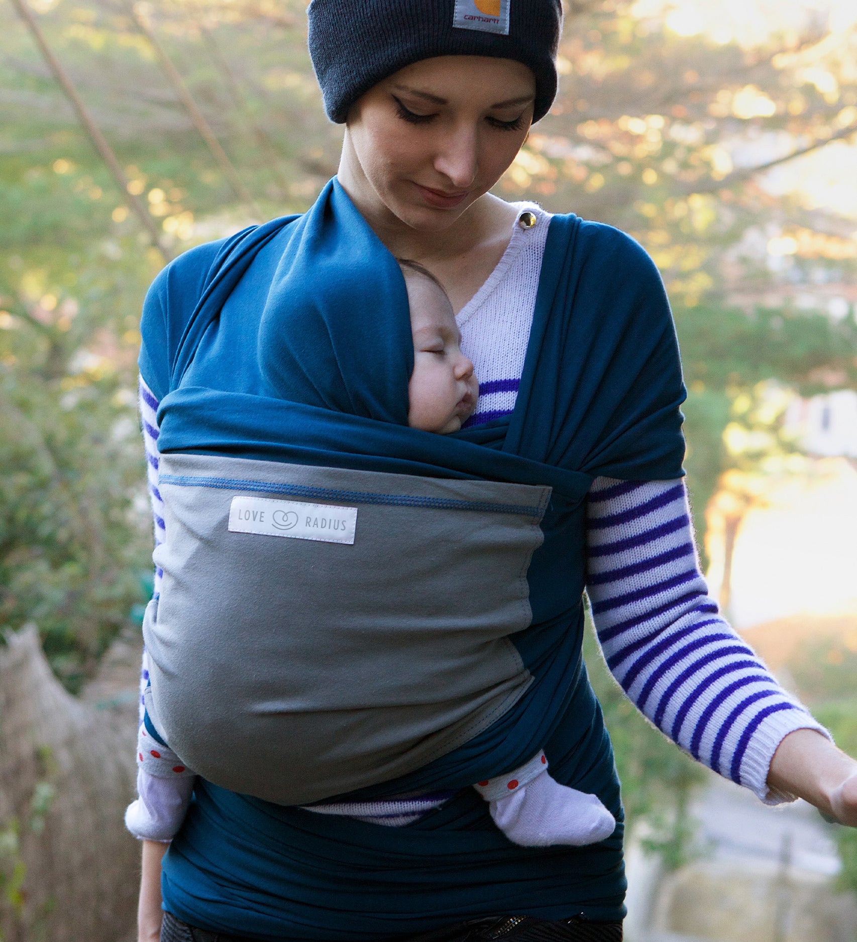 Adult carrying a baby in the Love Radius Original JPMBB Baby Wrap - peacock blue/elephant.