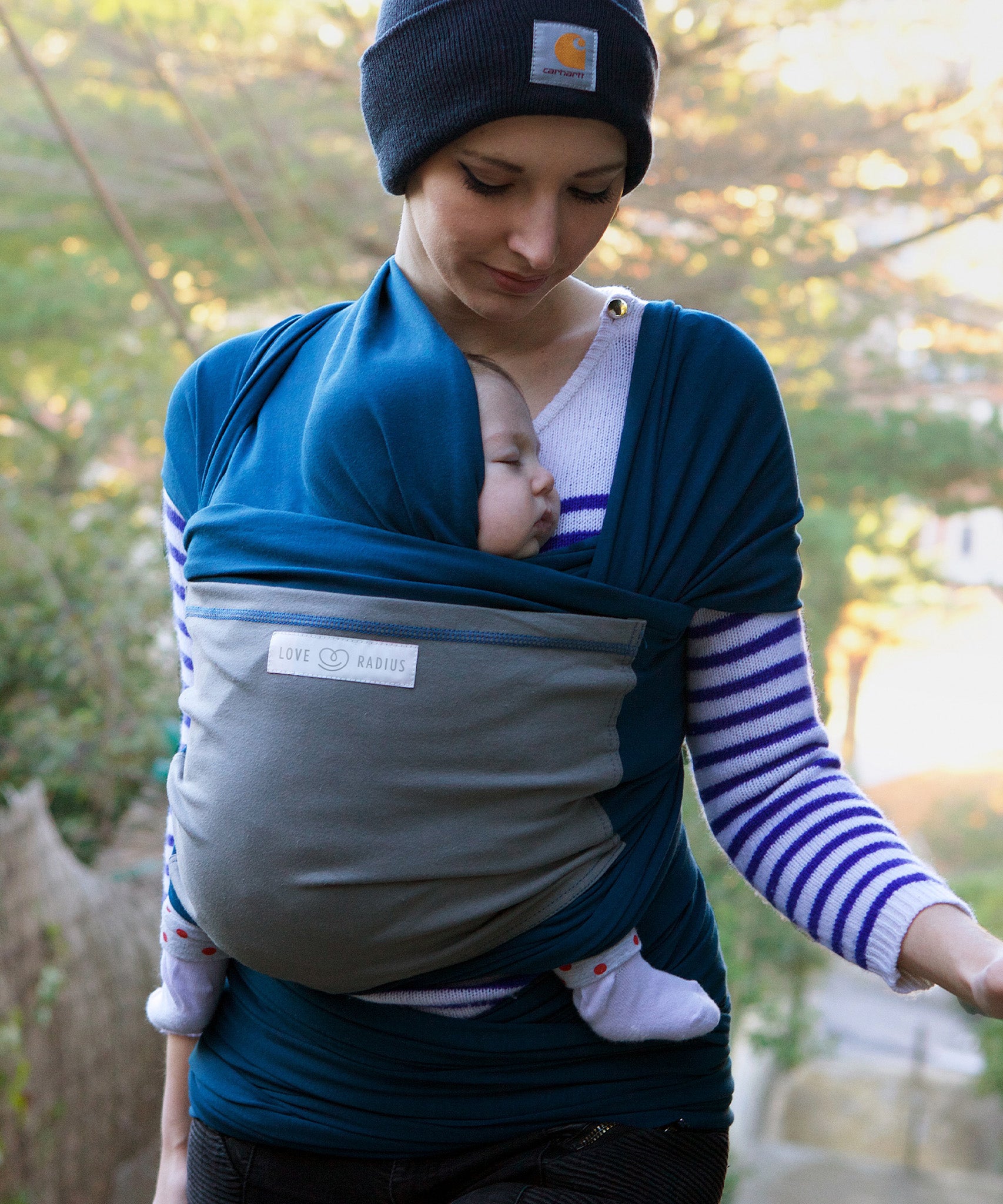 Adult carrying a baby in the Love Radius Original JPMBB Baby Wrap - peacock blue/elephant.