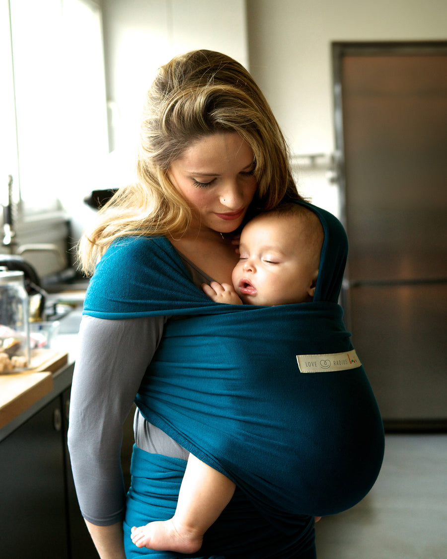 Adult carrying a baby in the Love Radius Organic Baby Wrap in Retro Blue. 