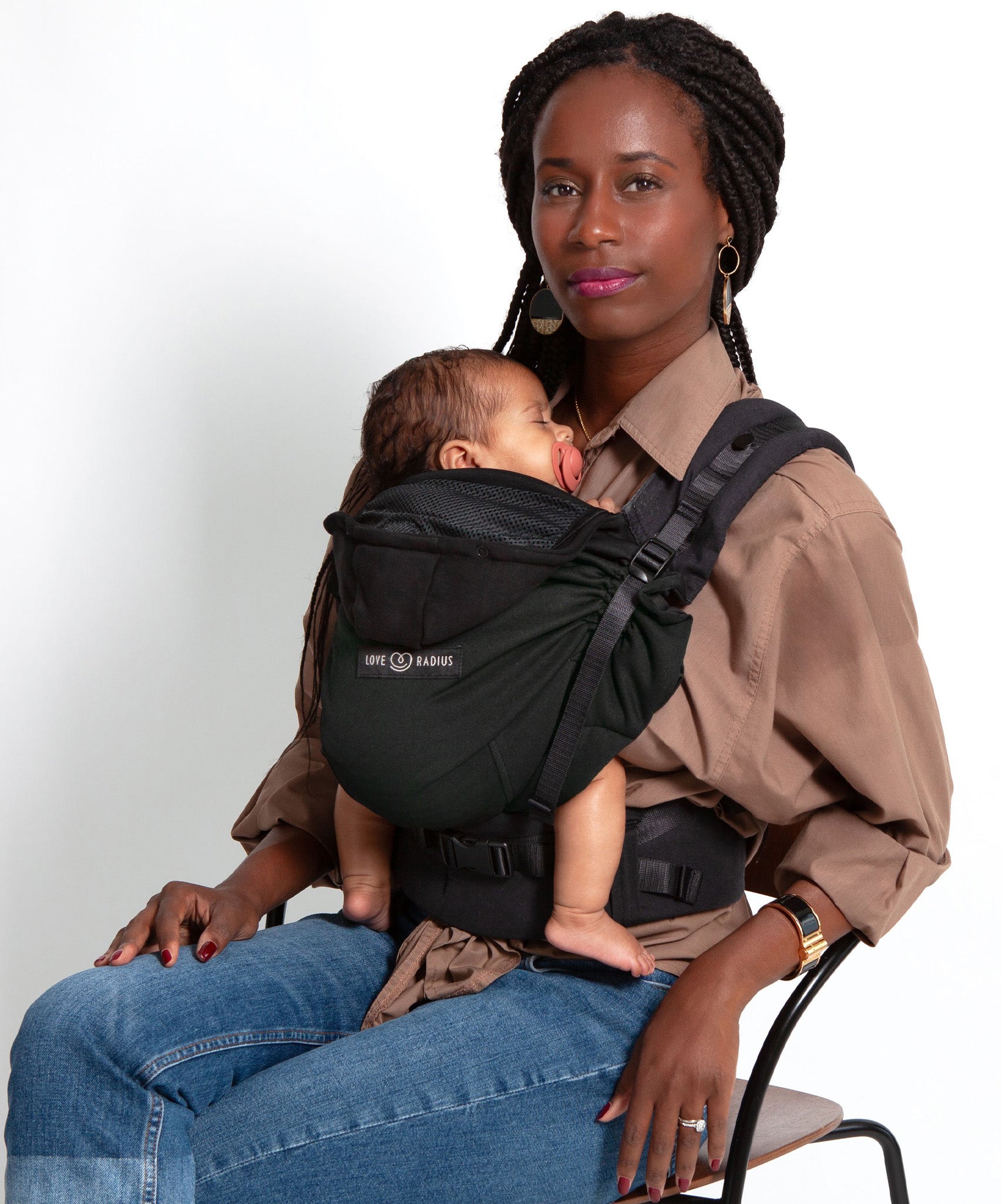 An adult carrying a baby in the Love Radius HoodieCarrier 2 - Black Forest. 