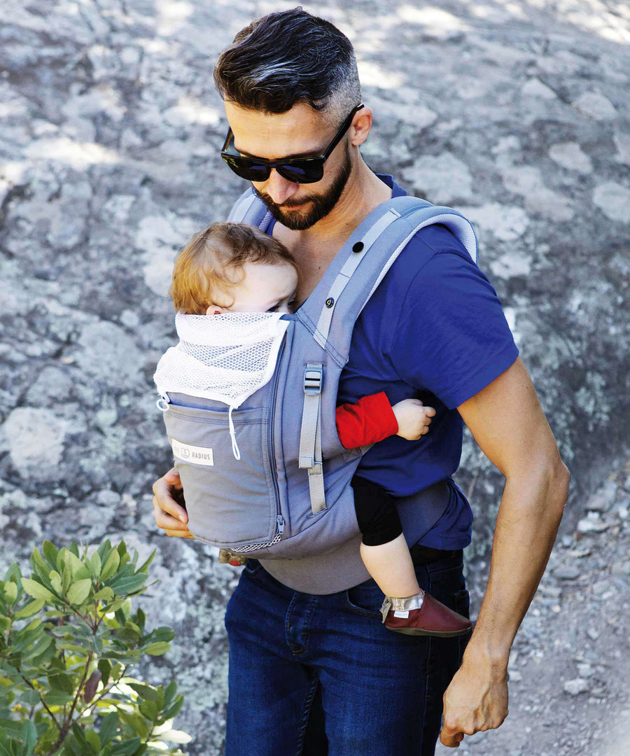 An adult carrying a baby in the Love Radius PhysioCarrier in Elephant.