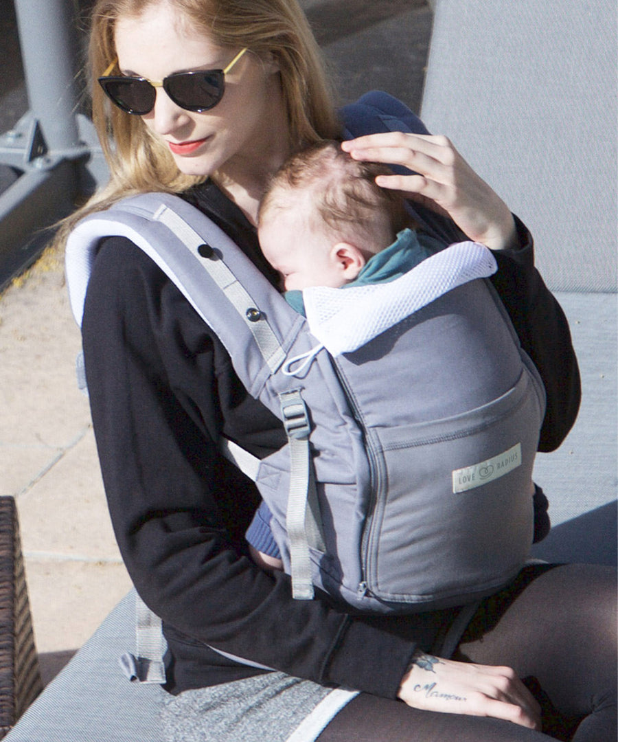 An adult carrying a baby in the Love Radius PhysioCarrier in Elephant.