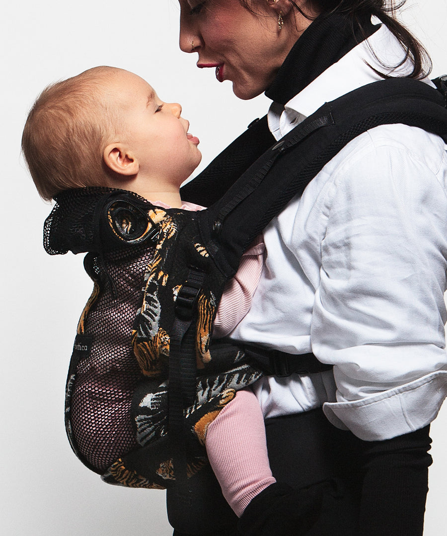 An adult carrying a baby in the Love Radius PhysioCarrier in Tiger.