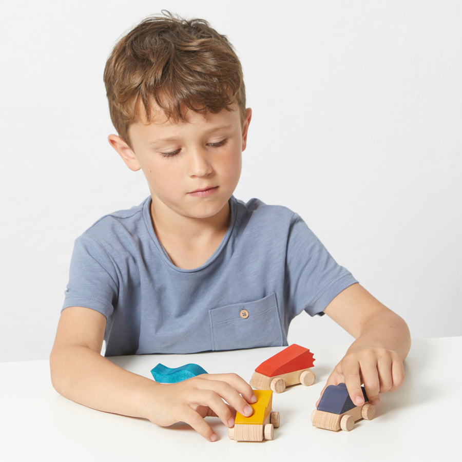 Child playing with the sustainably sourced beech wood supercar toys on a white table