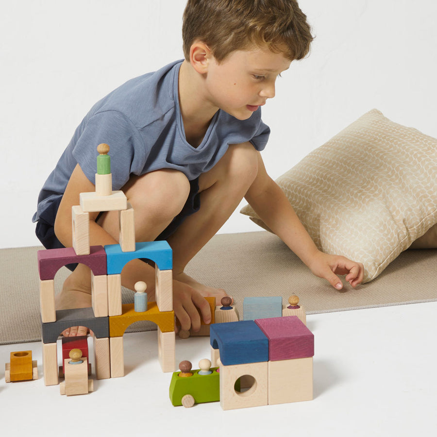 Boy playing with some Lubulona plastic free wooden stacking tunnels on a white floor