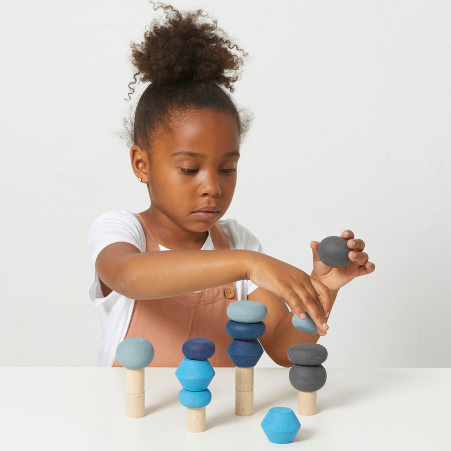 Girl playing with the eco-friendly Lubulona wooden stacking shape tree set on a white table