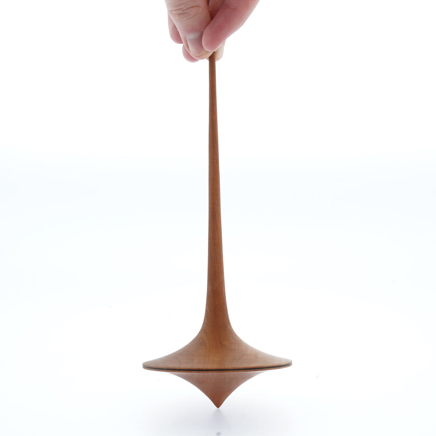 Close up of a hand spinning the Mader wooden Trumpo spinning top on a white background