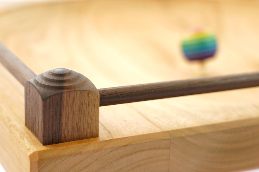 Close up of the walnut frame around the edge of a Mader handmade ash wood Manege spinning plate