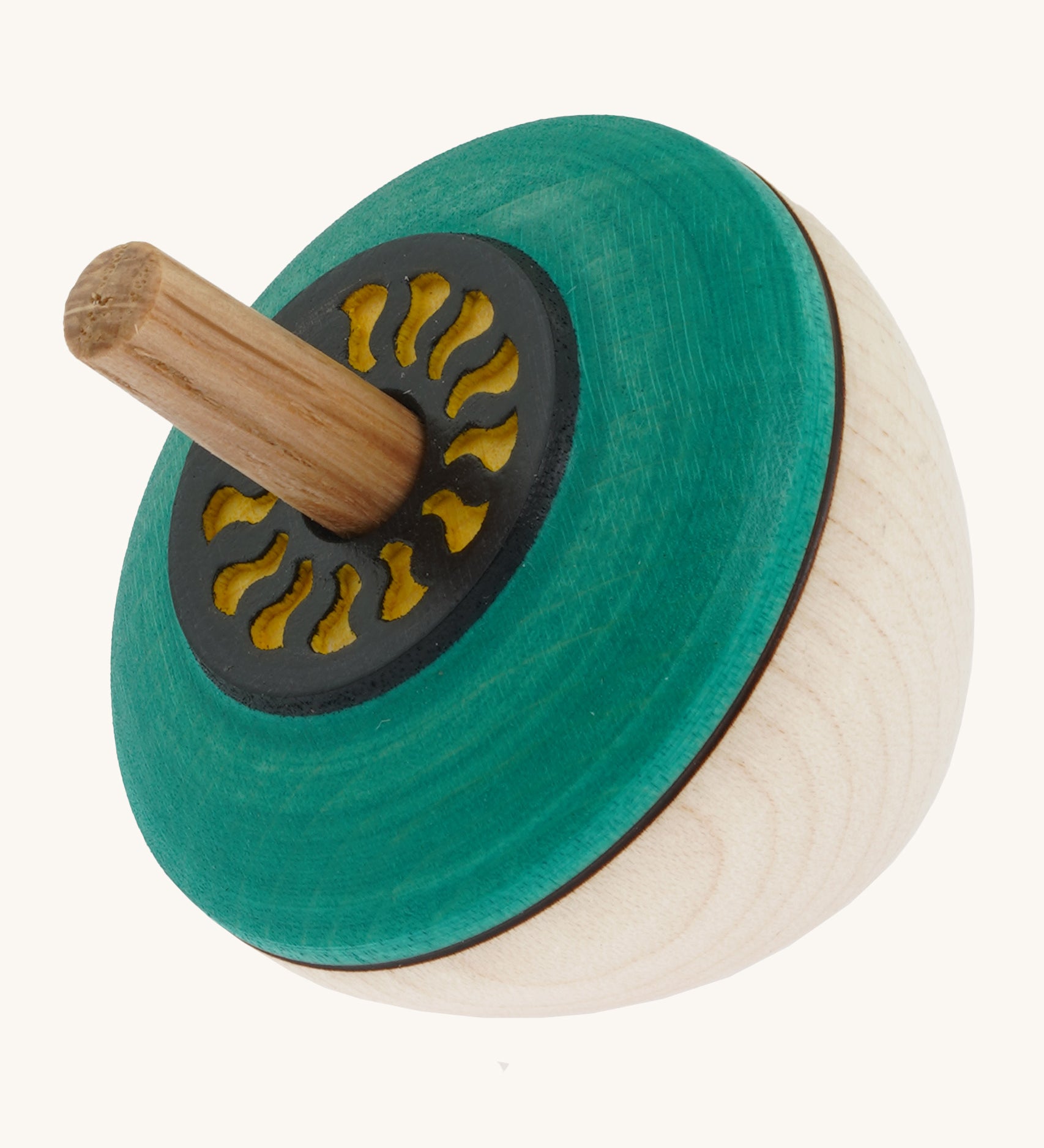 A wooden flower egg Mader spinning top with a green painted and  a yellow cut out design on the top on a cream background.