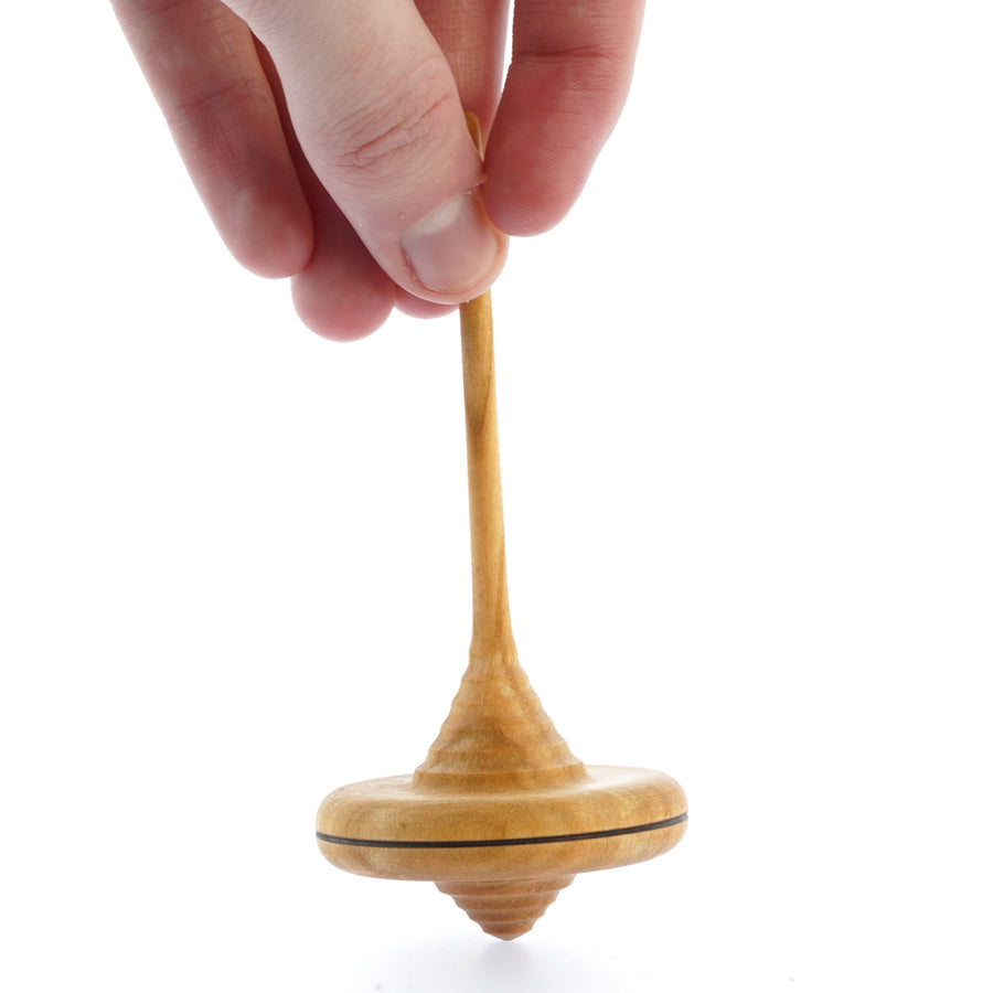 Close up of a hand holding the Mader plastic-free wooden Ibis spinning top on a white background