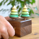 Close up of a hand turning the Mader wooden music box on a wooden table