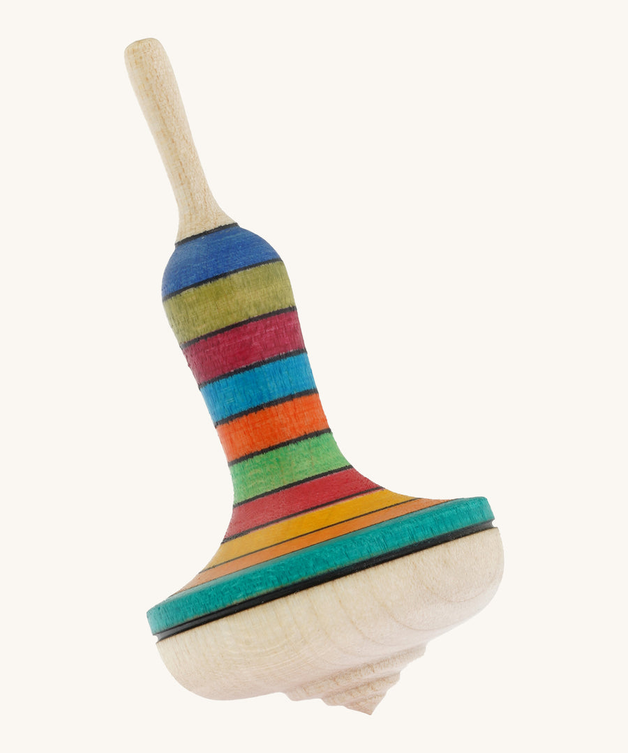 A wooden Mader manolette spinning top with a rainbow design on a cream background.