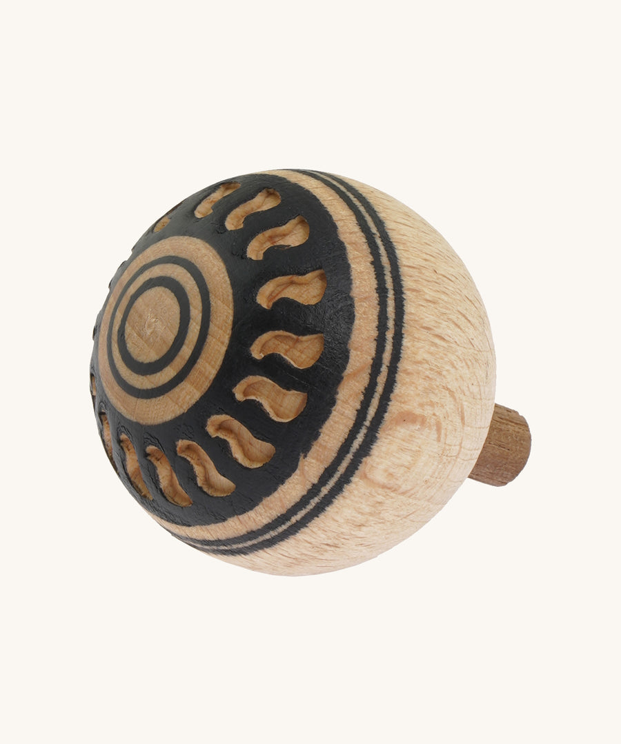 A wooden Mader Oriental turn over spinning top with a cut out pattern design on the bottom on a cream background.