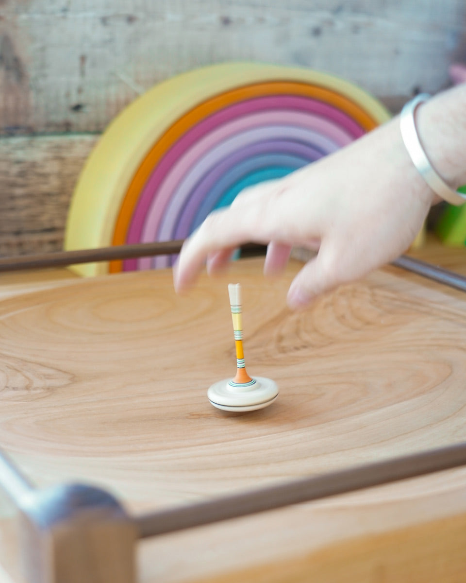 Mader handmade Manege wooden spinning plate on a wooden floor covered in various Mader spinning top toys