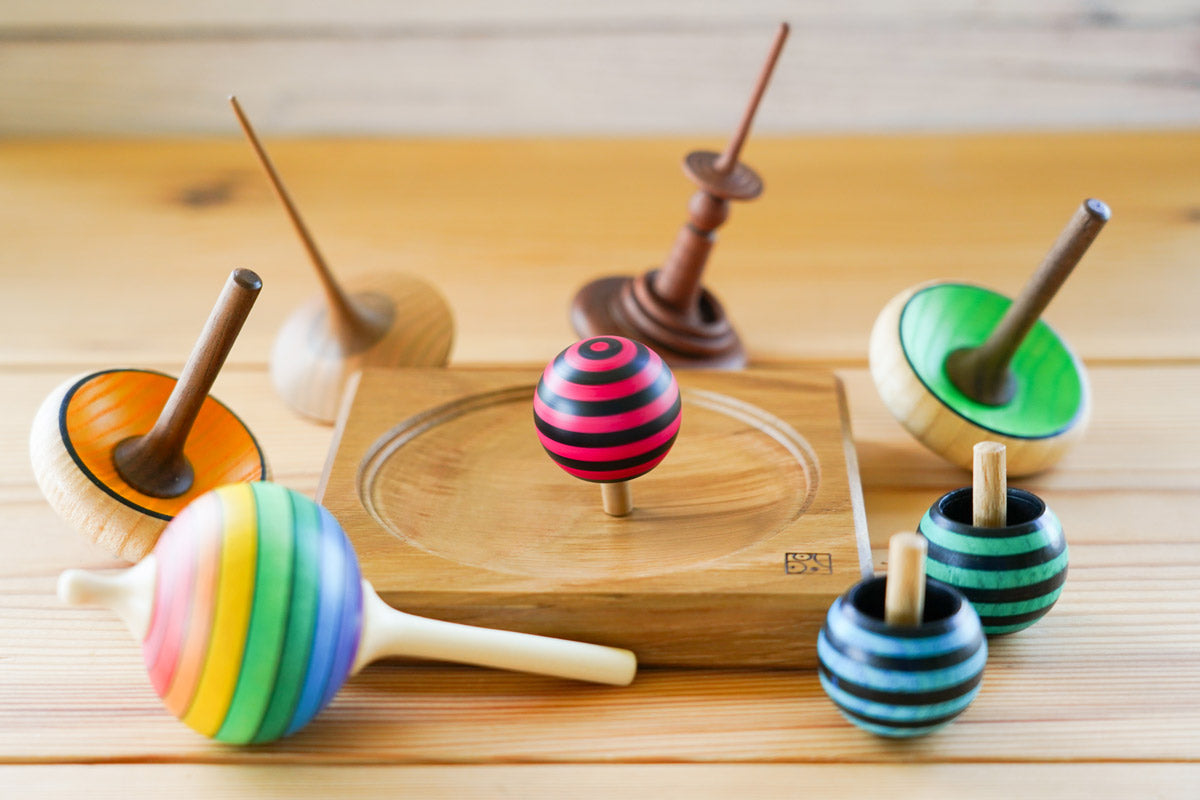 red and green Mader hand carved wooden tango turn over spinning top toys on a white background