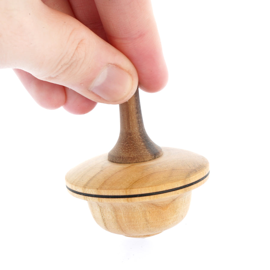 Close up of a hand spinning the Mader handmade Duet spinning top on a white background