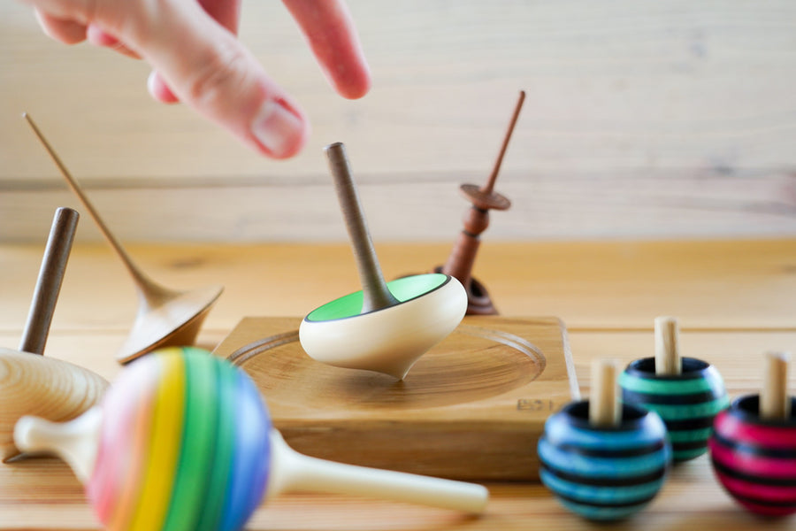 Close up of a hand spinning the Mader handmade wooden zwirbel spinning top on a Mader spinning plate