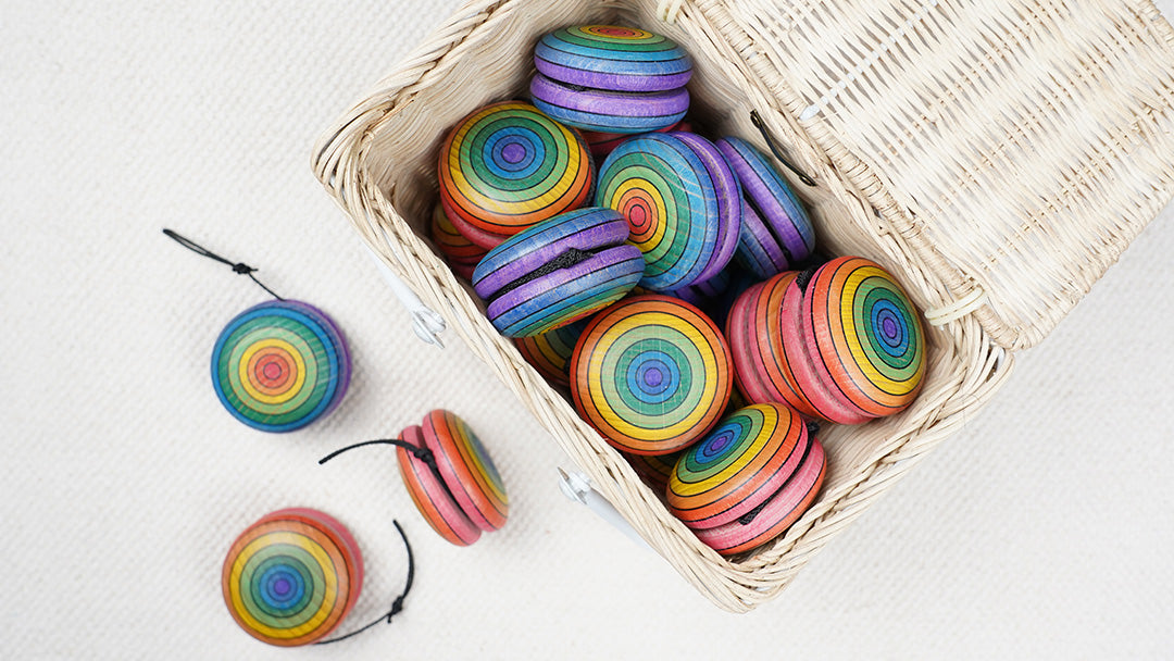 White basket filled with Mader wooden rainbow coloured yo-yos