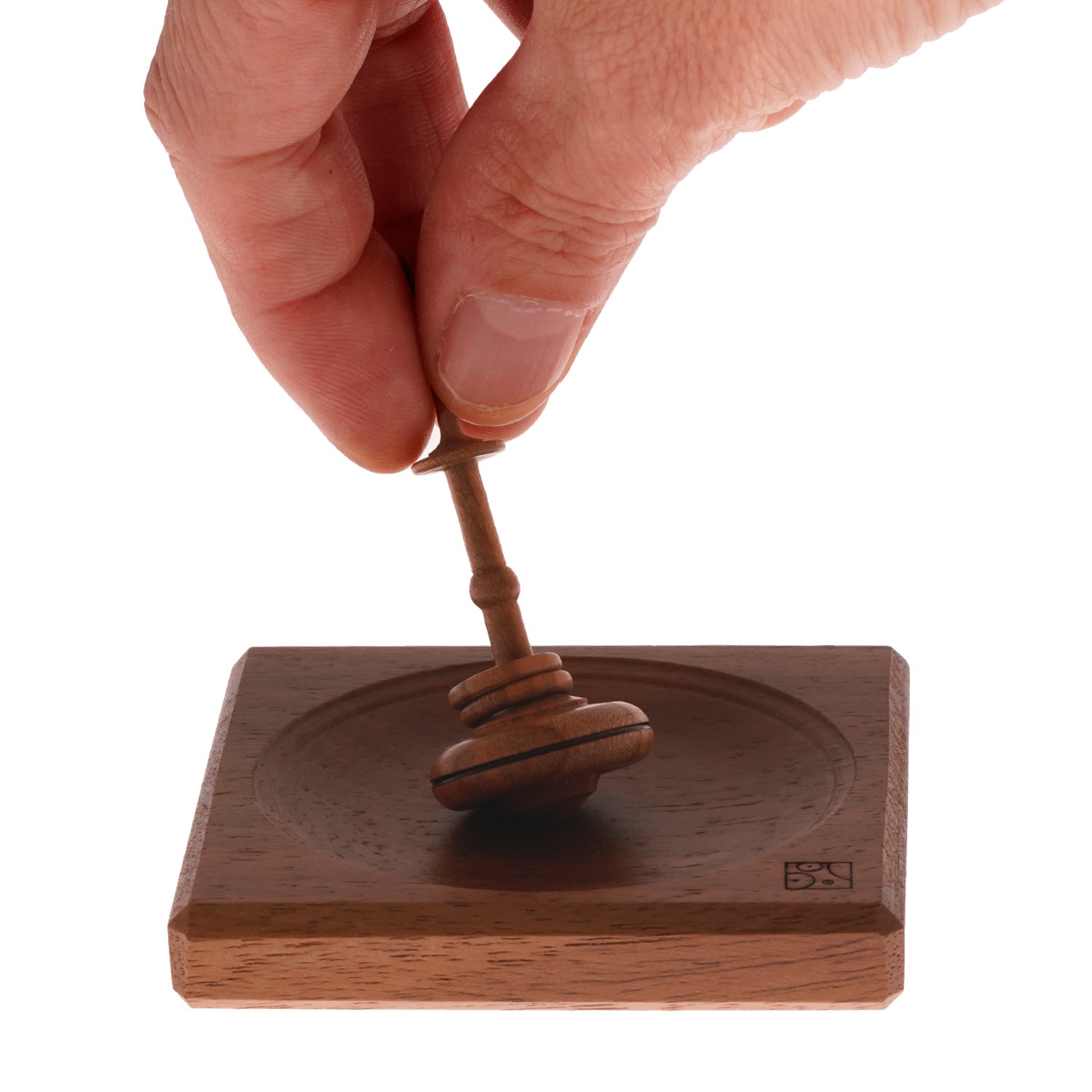 Mader Helene's Captive Rings Small Plum Spinning Top with Mini Board on a plain background. An adult hand spins the top to show the scale.