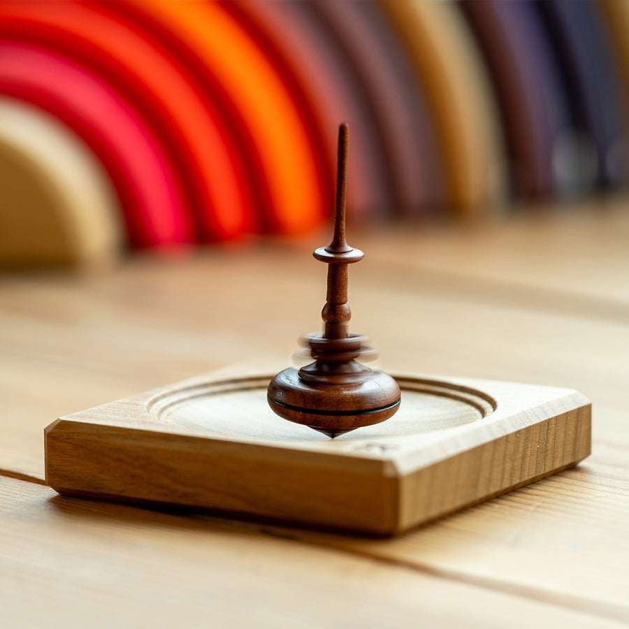 Mader Helene's Captive Rings Small Plum Spinning Top spins on a Mini Board.