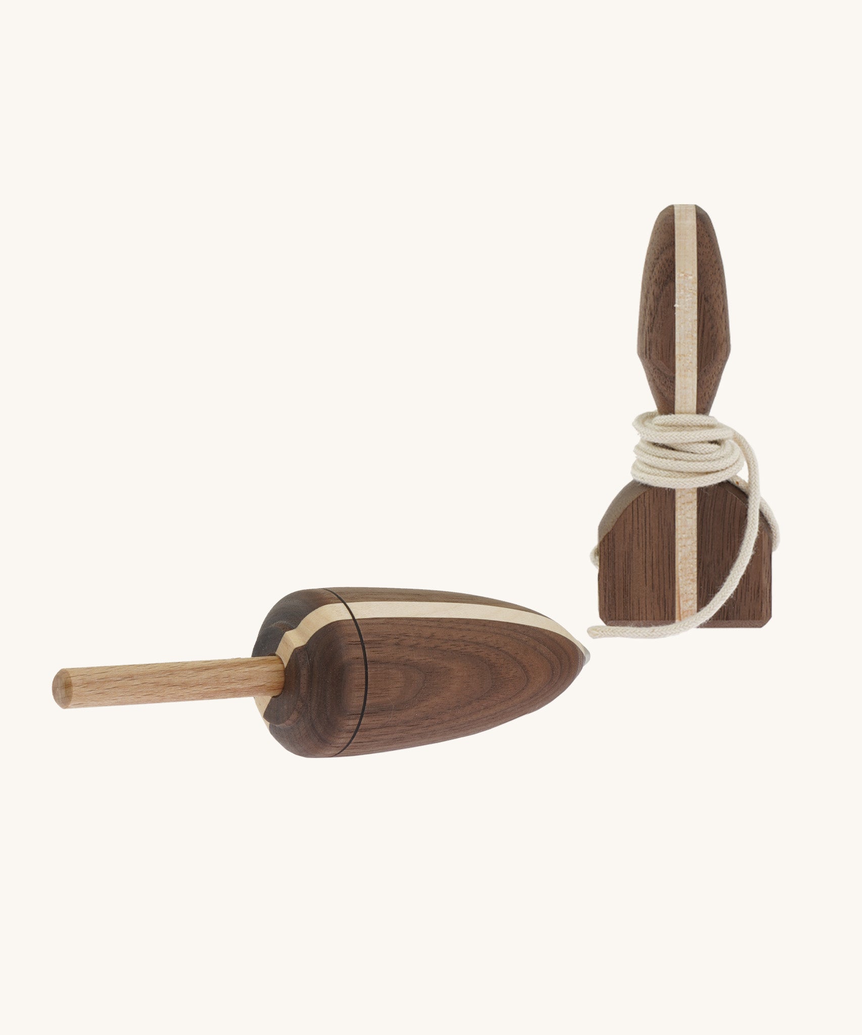 A wooden Mader Goliath spinning top with a light wood strip through the middle with a matching wooden starter on a cream background.