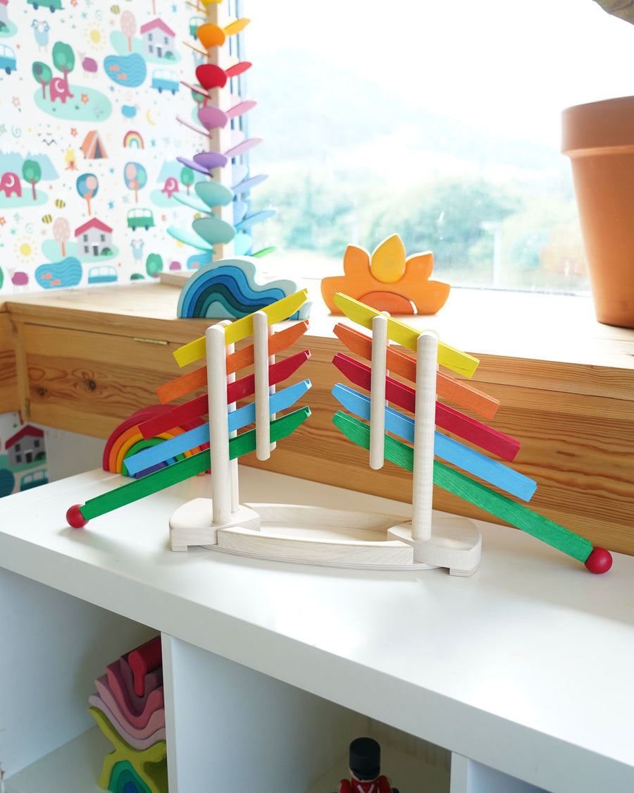 Magic Wood Reverse Ball Run pictured on white shelving in a playroom. A magic wood marble tree and Grimm's toys can be seen in the background