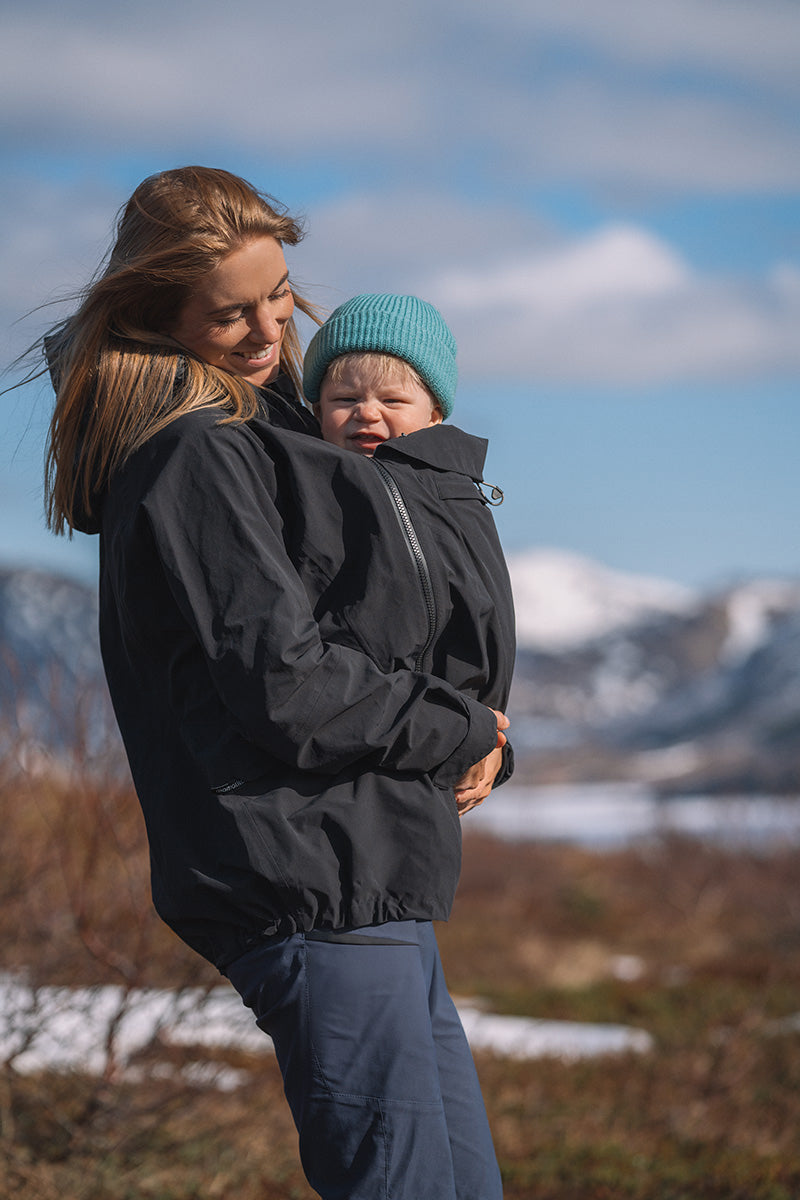 A person wearing the Mamalila Outdoor Explorer Babywearing Jacket - Mint