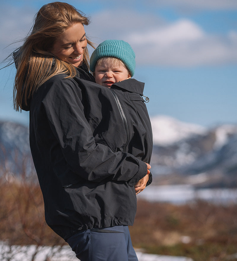 A person wearing the Mamalila Outdoor Explorer Babywearing Jacket - Mint