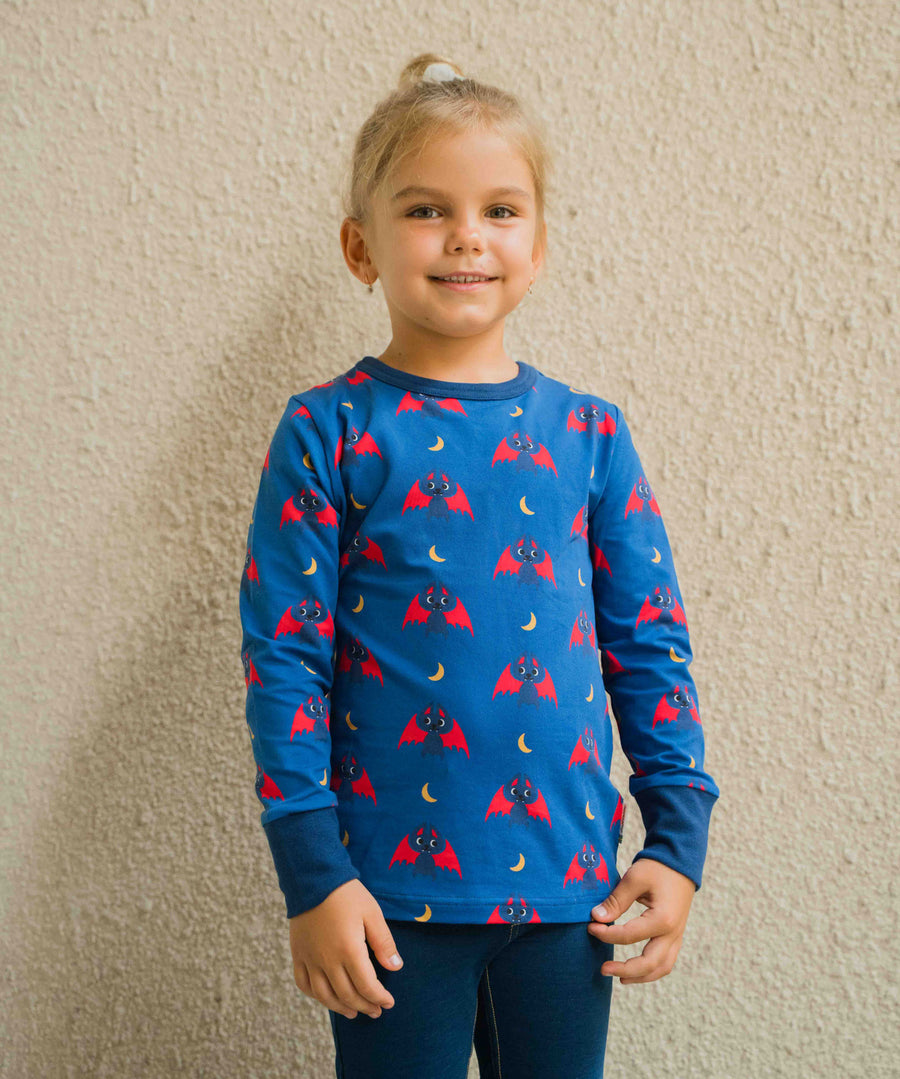 A child wearing the Maxomorra Bat Long Sleeve Top. the child is stood in front of a cream coloured wall. 