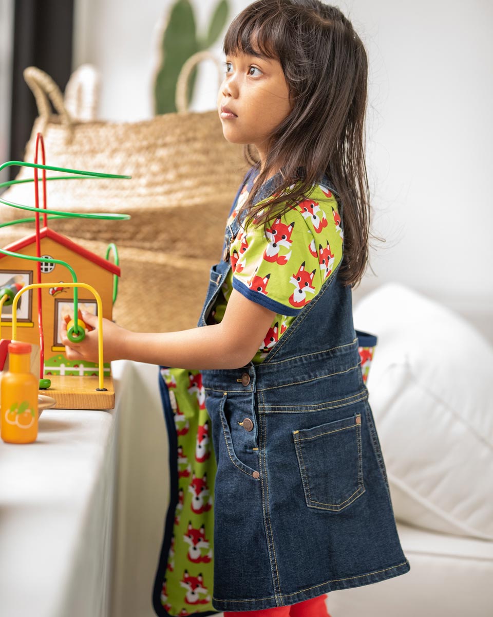 Girl stood up wearing the Maxomorra denim pinafore dress over the short sleeve organic cotton fox top