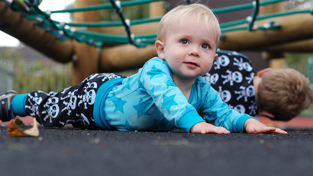 A baby in a playground wearing a funky Maxomorra outfit