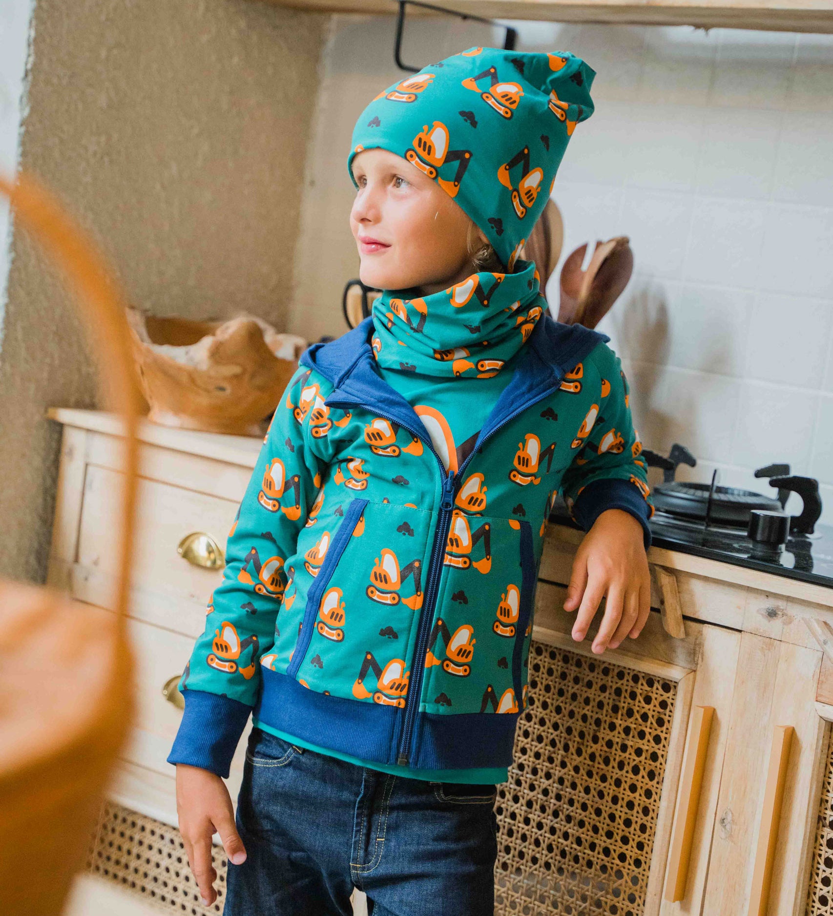 A child wearing a Maxomorra Excavator Reversible Zip Hoodie with matching hat and tube scarf.