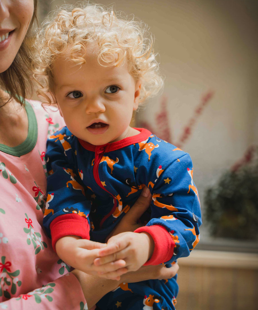 A close up of a young child wearing the Maxomorra Reindeer Long Sleeve Rompersuit.