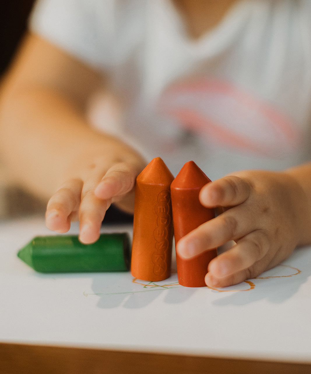 A small child holding Medenka's chunky beeswax crayons for little kids. 