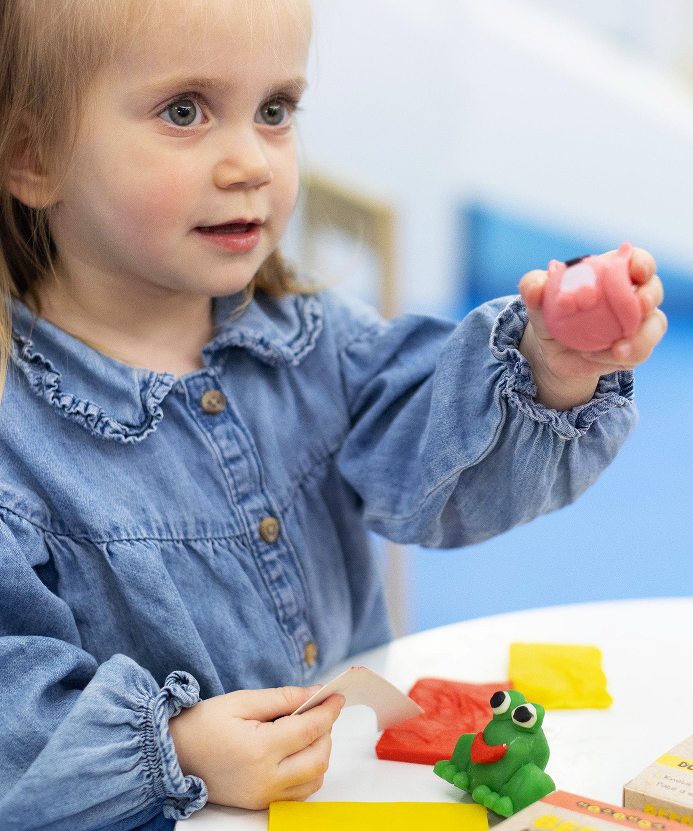  A little girl playing with some pink Medenka beeswax modelling clay. 