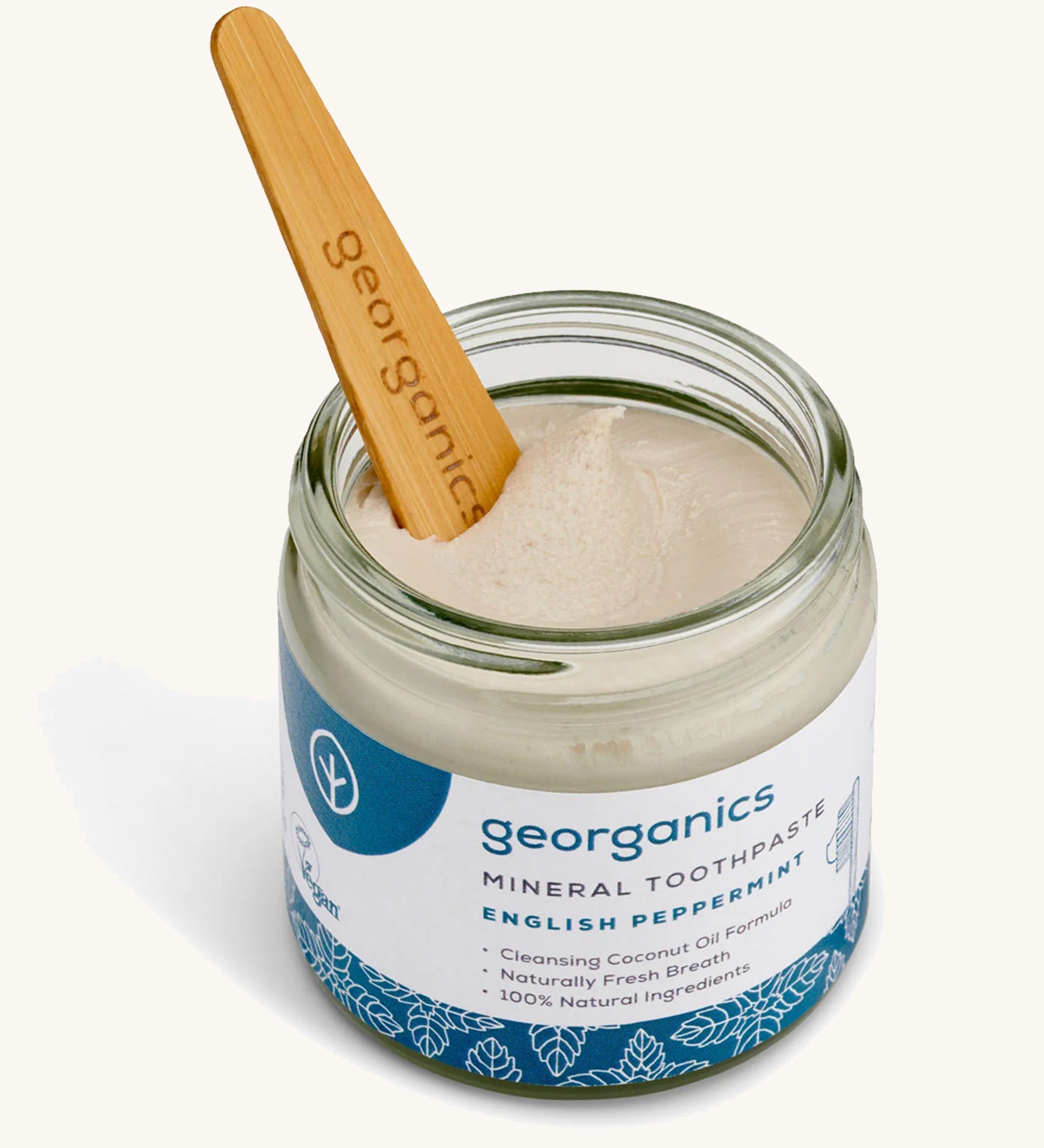 A opened jar of the Georganics english peppermint mineral toothpaste with the tongue stick dipped in