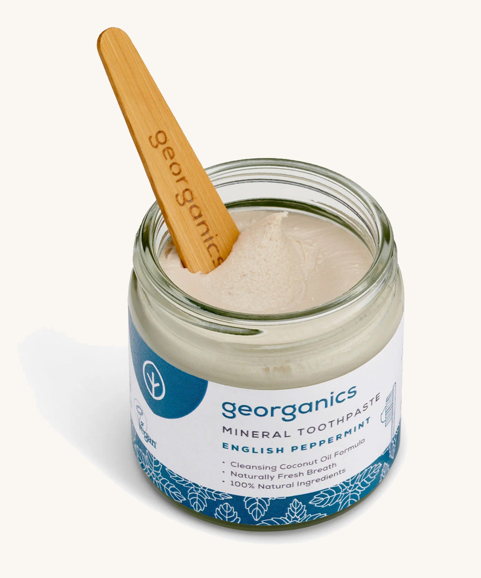 A opened jar of the Georganics english peppermint mineral toothpaste with the tongue stick dipped in