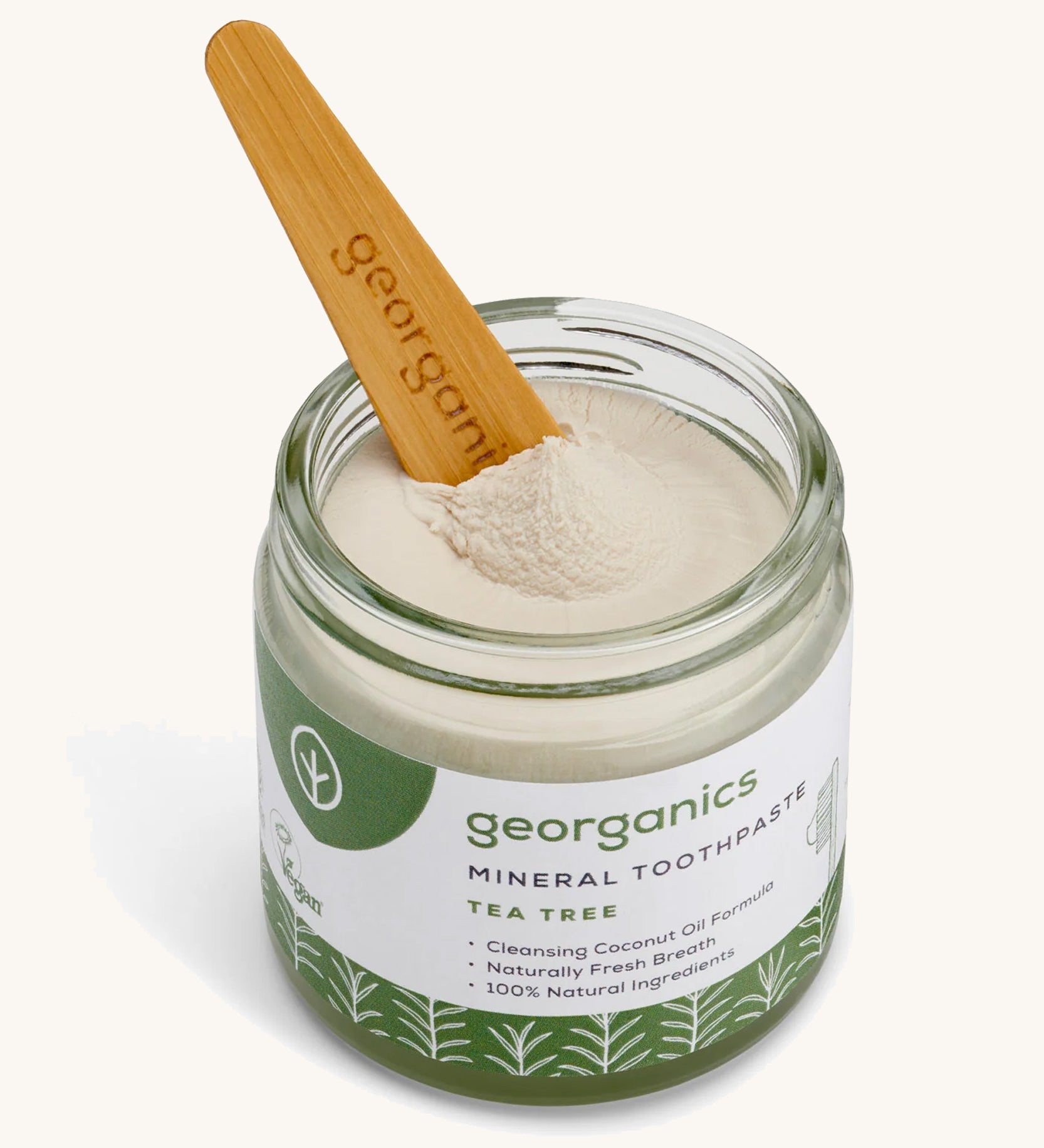 A opened jar of the Georganics tea tree mineral toothpaste with the tongue stick dipped in.