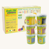 ÖkoNORM nawaro classic soft modelling clay set in natural colours. The packaging is a yellow and brown box with eco-friendly branding, featuring an illustration of an owl and colourful clay balls. Six small transparent tubs with green labels are stacked in front, each containing a different colour of soft, natural modelling clay, including yellow, black, red, brown, blue, and green. The product is labelled as non-toxic, biodegradable, and made from natural ingredients.