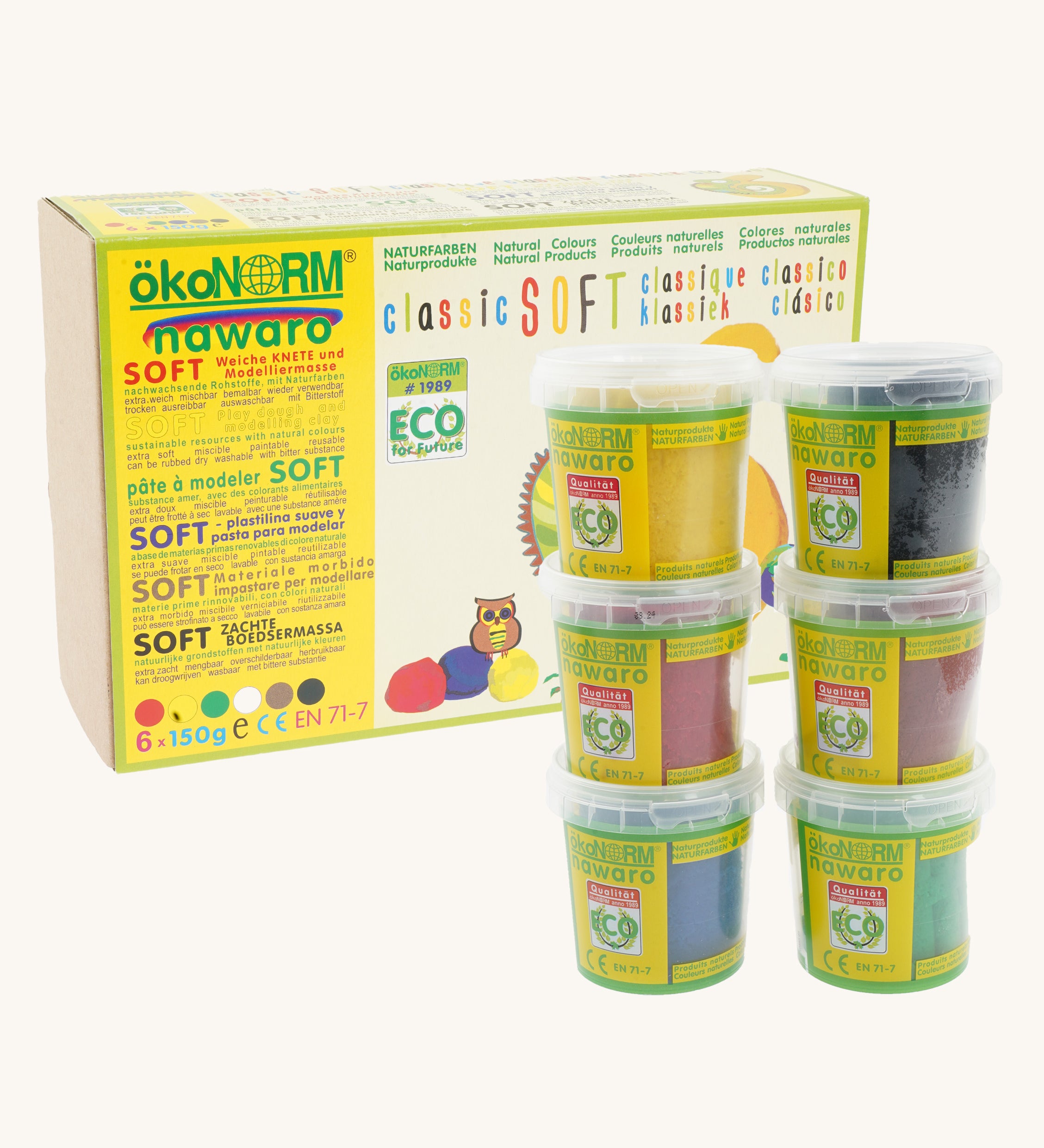 ÖkoNORM nawaro classic soft modelling clay set in natural colours. The packaging is a yellow and brown box with eco-friendly branding, featuring an illustration of an owl and colourful clay balls. Six small transparent tubs with green labels are stacked in front, each containing a different colour of soft, natural modelling clay, including yellow, black, red, brown, blue, and green. The product is labelled as non-toxic, biodegradable, and made from natural ingredients.