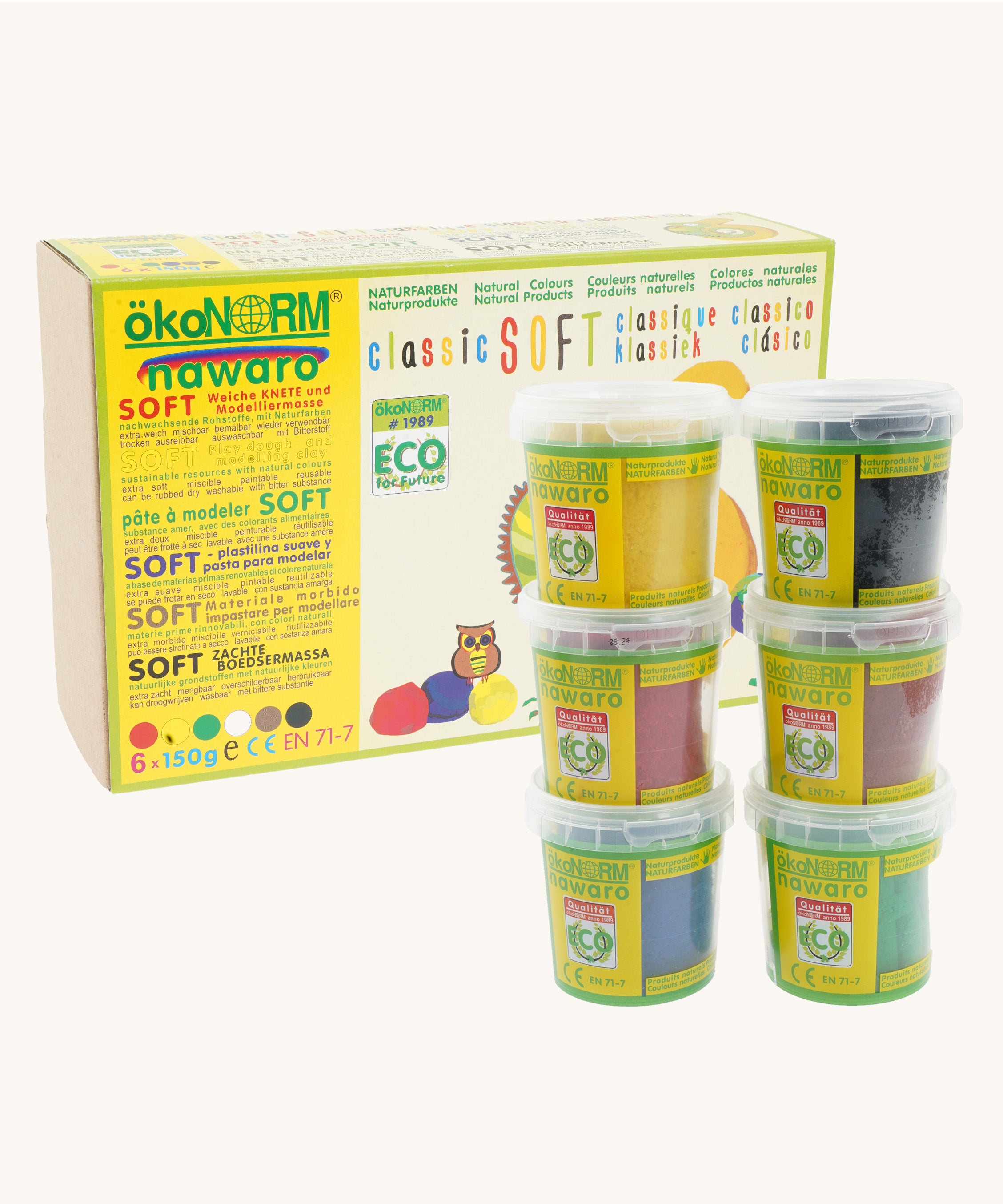 ÖkoNORM nawaro classic soft modelling clay set in natural colours. The packaging is a yellow and brown box with eco-friendly branding, featuring an illustration of an owl and colourful clay balls. Six small transparent tubs with green labels are stacked in front, each containing a different colour of soft, natural modelling clay, including yellow, black, red, brown, blue, and green. The product is labelled as non-toxic, biodegradable, and made from natural ingredients.