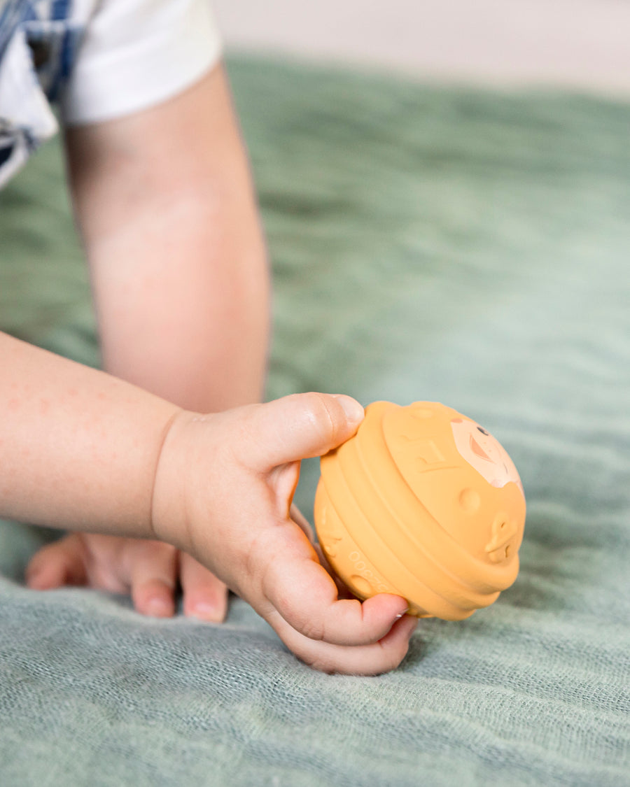 A childs hand holing the yellow ball from the Sophie The Giraffe - Once Upon A Time 5 Senses Musical Balls