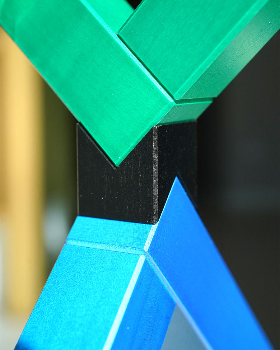 Angular construction toy from Naef arranged in a complex geometric stack in front of a white background.